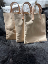 Load image into Gallery viewer, natural vegetable tanned leather bags small size, narrow-rectangular flat shape. two veg tan handles attached/sewn using belgian linen yarn. also made in distressed brown & black leather and black & tan suede. Retail price $195.