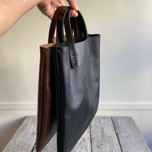 Load image into Gallery viewer, Black and brown leather bags small size, narrow-rectangular flat shape. two veg tan handles attached/sewn using belgian linen yarn. also made in natural vegetable tanned leather and black & tan suede. Retail price $195.