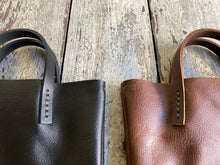 Load image into Gallery viewer, Black and brown leather bags small size, narrow-rectangular flat shape. two veg tan handles attached/sewn using belgian linen yarn. also made in natural vegetable tanned leather and black & tan suede. Retail price $195.